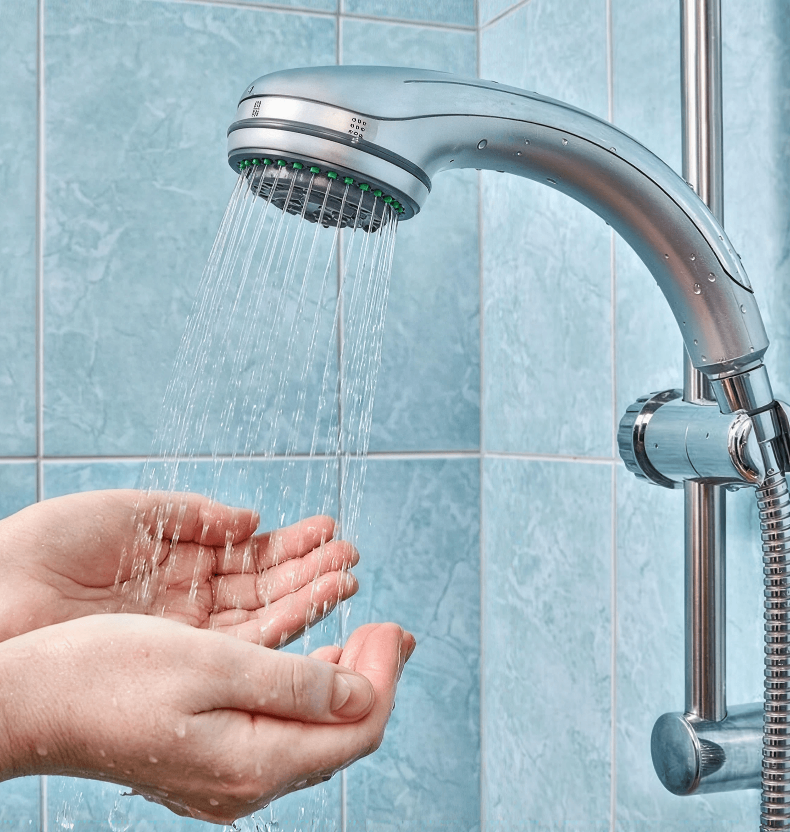 Hands catching water from a silver shower head, against blue tiled wall. The scene conveys freshness and cleanliness in a bathroom setting.