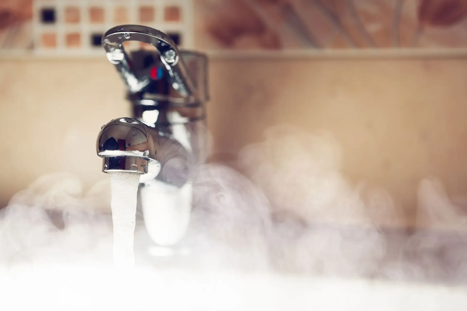A chrome faucet releases a steady stream of hot water, producing visible steam. The blurred background suggests a bathroom setting, conveying warmth.